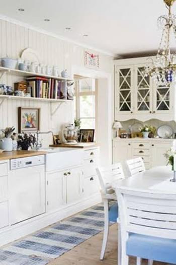 A cute white Swedish kitchen with a worn flat-weave rug. 