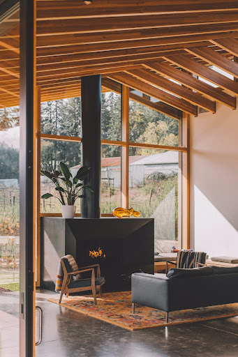 Open living room concept with poured concrete floors, modern fireplace, and vintage persian rug with large windows.