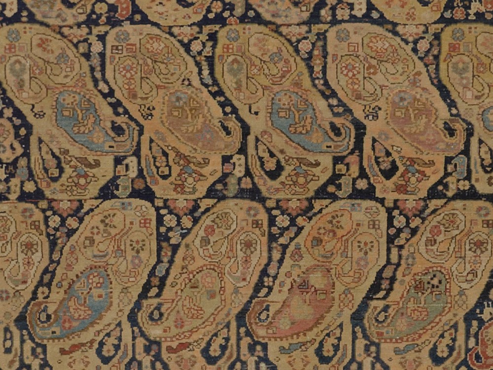 Close-up of a muted Oriental rug in black, tan, light blue, maroon, and more.