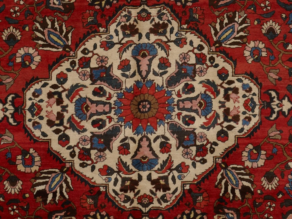 An example in deep red, taupe, blues, and other colors of a rosette and palmette Oriental rug design.